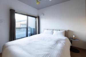 a bedroom with a large white bed with a window at Bio Top Apartment Stay in Fukuoka
