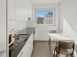 a white kitchen with a table and a window at Cozy 1BR near lake with balcony - Mill 422 in Zurich