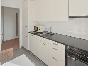 a white kitchen with a sink and a microwave at Cozy 1BR near lake with balcony - Mill 422 in Zurich +2 photos