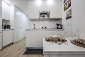 a kitchen with white cabinets and a table with glasses at Fancy Studio with Terrace & Pool - Madrid South in Villaverde
