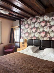 a bedroom with a bed and a floral wall at Hotel Au Cerf in Riquewihr