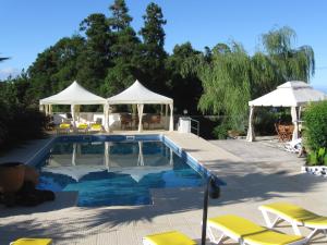 a swimming pool with yellow chairs and umbrellas at Quinta do Rossio, Rural Tourism in Biscoitos