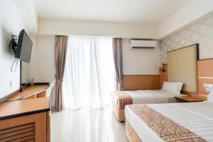 a hotel room with two beds and a flat screen tv at Sipadan Inn 3 in Semporna