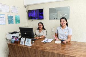 two women sitting at a counter with a laptop at San Felipe Hotel in Colinas do Tocantins