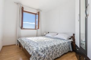a white bedroom with a bed with a window at Sweet Escape in Makarska