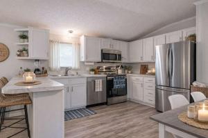 a kitchen with white cabinets and a stainless steel refrigerator at Rough River Lake Cabin Fishing in Fentress McMahan +99 photos