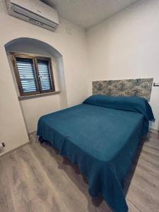 a bedroom with a bed with a blue bedspread and a window at Casa CAMILLA in Vasto