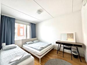a bedroom with two beds and a desk and a window at Warm and cozy one-bedroom & Sauna in Vantaa