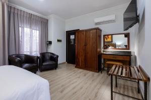 a room with a bed and a desk and chairs at Basdenwood Hotel in Centurion