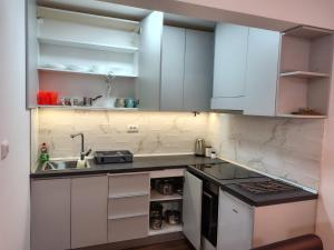 a kitchen with white cabinets and a sink at Apartmani Planinski Bor in Divčibare +4 photos