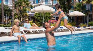 a man and two children jumping in a swimming pool at htop Planamar - Fun in Malgrat de Mar