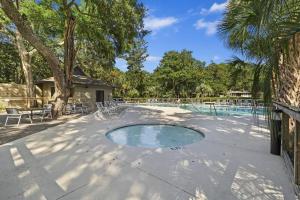 a swimming pool with chairs and a tree at IC106: 106 Inlet Cove in Kiawah Island