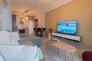 a living room with a couch and a flat screen tv at Aeris Apartment by Booking Kottas in Nea Moudania