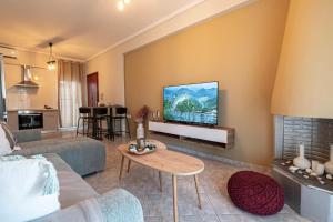 a living room with a couch and a tv on a wall at Aeris Apartment by Booking Kottas in Nea Moudania