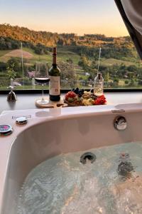 a bath tub with a bottle of wine and a glass at Sky chalé - Refúgio Da Lua in Ametista do Sul +17 photos