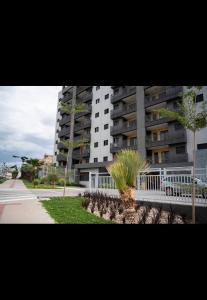 a large apartment building with palm trees in front of it at Cozy Moov Smart Apartamento in Cuiabá
