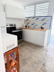 a kitchen with white cabinets and a counter top at Charming 3BR Near Ponce Attractions in Ponce +2 photos