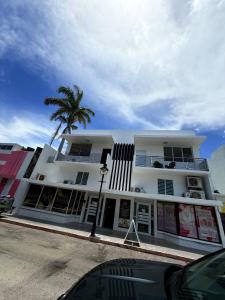a white building with a palm tree in front of it at Charming 3BR Near Ponce Attractions in Ponce
