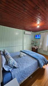 a bedroom with a bed with blue sheets and a tv at Casa Privativa no Centro de Urubici - Casa Doce Luar in Urubici +36 photos