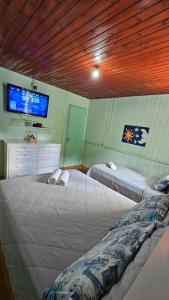 a bedroom with two beds and a tv on the wall at Casa Privativa no Centro de Urubici - Casa Doce Luar in Urubici