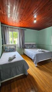 two beds in a room with a wooden ceiling at Casa Privativa no Centro de Urubici - Casa Doce Luar in Urubici