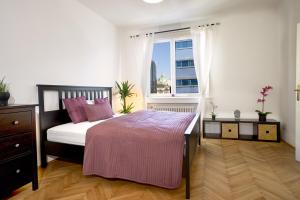 - une chambre avec un lit doté d'oreillers roses et d'une fenêtre dans l'établissement OPERASTREET CITY CENTER Apartment "Bangkok" in Vienna, à Vienne