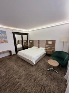 a bedroom with a bed and a green chair at White Residence in Arad