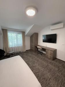 a hotel room with a bed and a desk and a television at White Residence in Arad