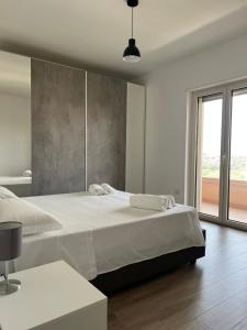 a white bedroom with two beds and a large window at Apartment Le Forge in Policoro