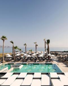 a pool with chairs and umbrellas and the ocean at Kooba Villas in Gázion