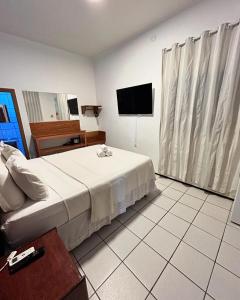 a bedroom with a bed and a flat screen tv at Beach House Suítes Jeri in Jericoacoara