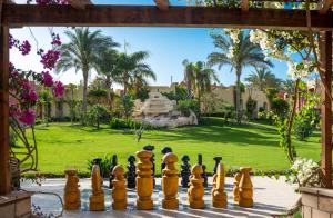 a chessboard in front of a garden with palm trees at Cardina Resort in Marsa Alam City