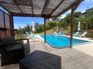 a patio with a swimming pool and chairs at Case Géranium 2* piscine chauffée in Saint-Joseph