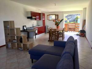 a living room with a blue couch and a kitchen at Case Géranium 2* piscine chauffée in Saint-Joseph
