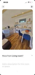 a kitchen with a table and a blue chair at Lovely garden cabin in Luton