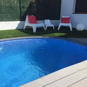2 sillas rojas y blancas y una piscina en Casa Azul, en Riumar