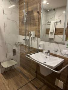 a bathroom with a white sink and a shower at Optima Collection Bergshloss Rivne in Rivne