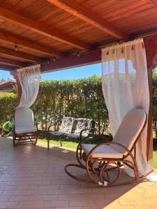 a patio with two chairs and curtains on a patio at Casa Malò 2 in Ovile la Marinella