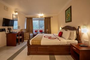 a bedroom with a bed and a desk in a room at Las Palmas in Munnar