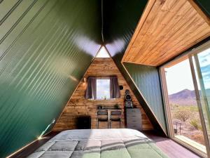 a bedroom in a tiny house with a green wall at Starwalk Modern A-Frame #1 in Meadview