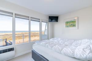 a bedroom with a bed and a view of the beach at Appartementencomplex Juliana 152 in De Koog