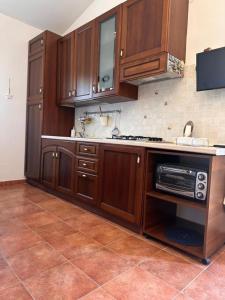 a kitchen with wooden cabinets and a microwave at Casa Malò 2 in Ovile la Marinella
