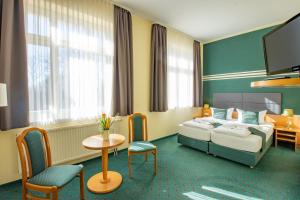 a hotel room with a bed and a table and chairs at Ferien Hotel Villa Südharz in Sülzhayn