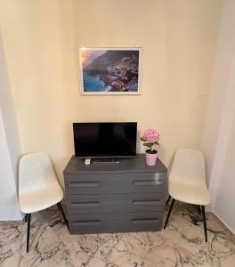 a living room with two chairs and a television on a dresser at Casa dell'Aloe in Angri
