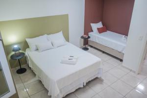 a hotel room with two beds with white sheets at Apartamento Brisa in Veranópolis