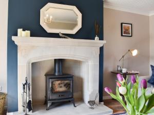 a fireplace with a mirror above it in a living room at Mill Lea Cottage in Leek