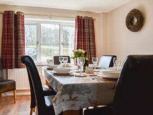 a dining room table with chairs and a large window at Mill Lea Cottage in Leek