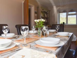 a dining room table with white plates and glasses at Mill Lea Cottage in Leek