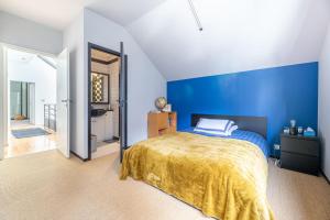 a bedroom with blue walls and a bed with a yellow blanket at Large fully renovated 250m house in Nantes