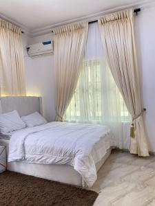 a bedroom with a white bed and a large window at Living Space Home in Lekki